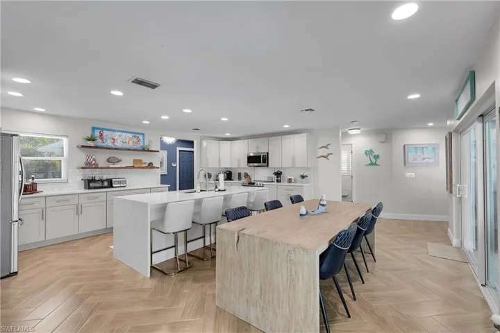 Open-concept kitchen and dining area featuring light-toned wood-finish flooring in a herringbone pattern