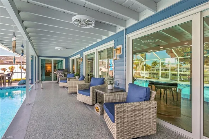 Covered patio featuring a speckled concrete finish, overhead lighting, and multiple sliding glass doors