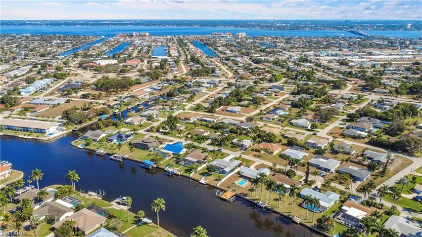 Canal-front community featuring numerous residential properties with private docks, direct water access, mature palm trees, and proximity to expansive waterways