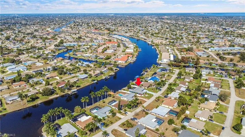 Canal-front property featuring a private dock and mature palm trees