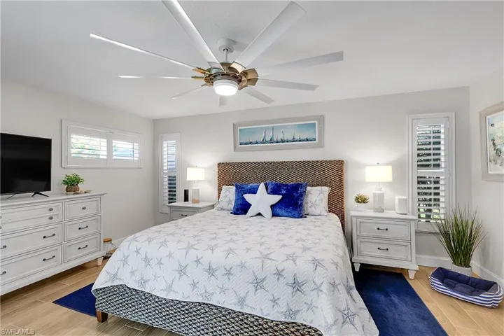 Spacious room featuring wood-finish flooring, white walls, and a large ceiling fan with integrated lighting