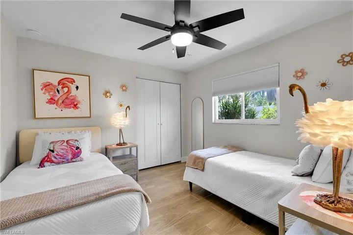 Room featuring wood-finish flooring, a contemporary ceiling fan with integrated lighting, and a window with a roller shade