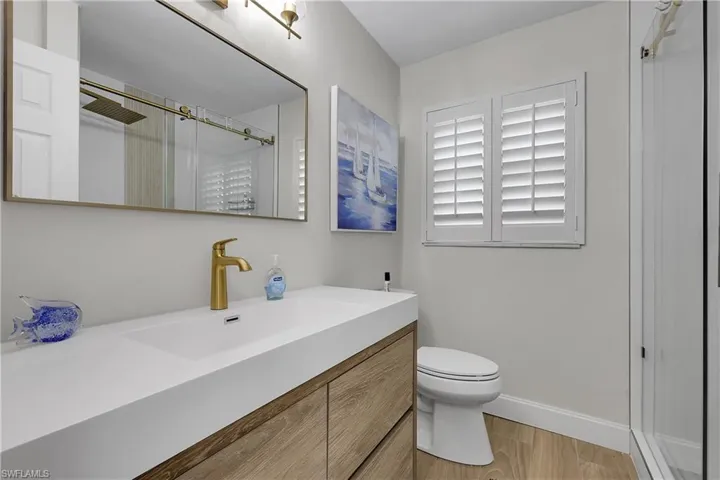 Bathroom featuring a modern vanity with an integrated sink, wood-finish cabinetry, and a gold-tone faucet