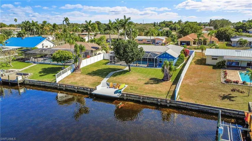 Waterfront property featuring a private dock, concrete seawall, and a screened swimming pool enclosure
