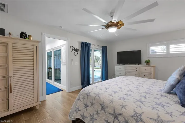 Bedroom featuring wood-finish tile flooring, a multi-blade ceiling fan with integrated lighting, and white walls