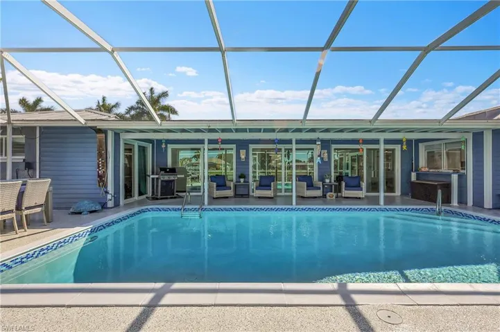 Screened-in outdoor pool featuring a mosaic tile border and integrated steps