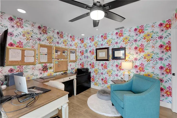 Interior room featuring decorative floral-patterned wallpaper, flush-mount lighting, and a ceiling fan with light fixture