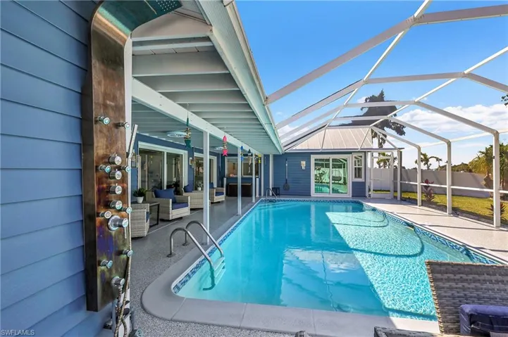 Screened lanai featuring a swimming pool with integrated steps, a poolside outdoor shower with multiple spray functions, and a covered patio area with a textured concrete finish