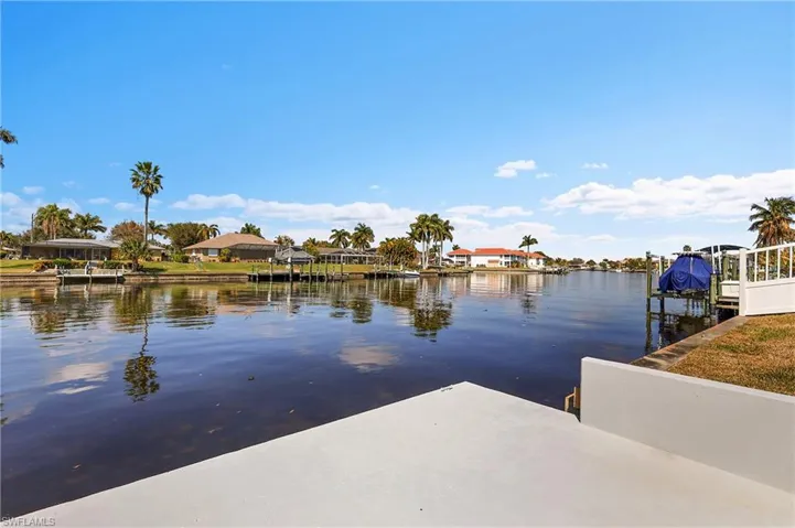 Waterfront canal with dock by residences and mature palm trees