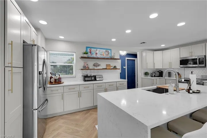 Kitchen featuring an expansive white countertop island with an integrated sink and gooseneck faucet