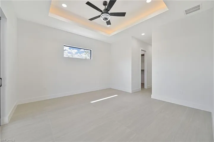 Unfurnished room featuring a ceiling fan, recessed lighting, and a tray ceiling