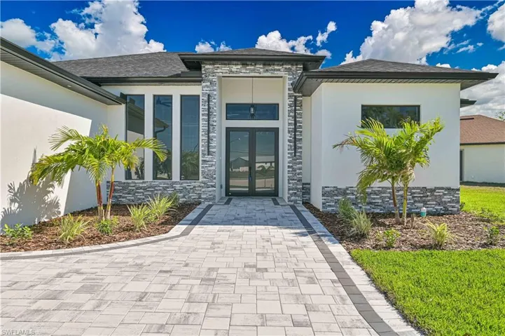 Doorway to property featuring french doors, stucco siding, stone siding, and roof with shingles