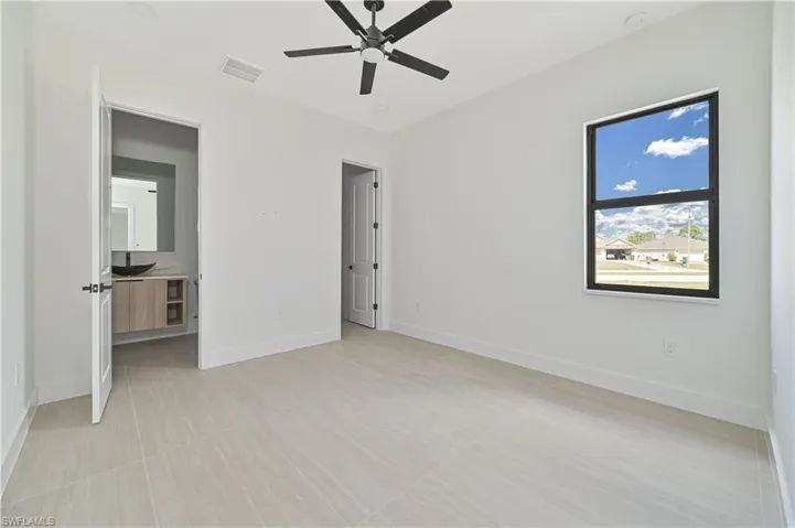 Unfurnished bedroom featuring a ceiling fan and connected bathroom
