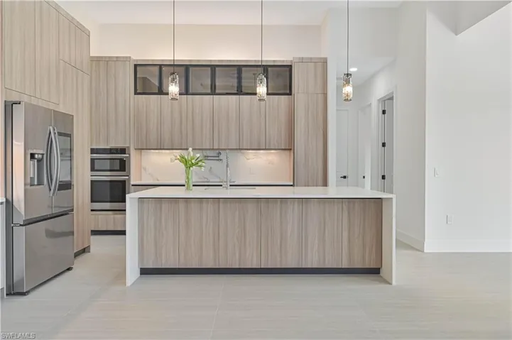 Kitchen with modern cabinets, stainless steel appliances, light stone countertops, and a spacious island