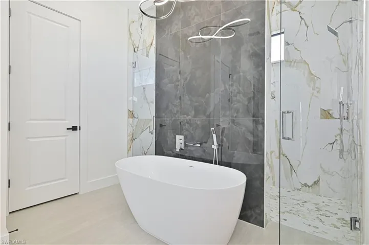 Full bath with a marble finish shower, tile walls, and a freestanding tub