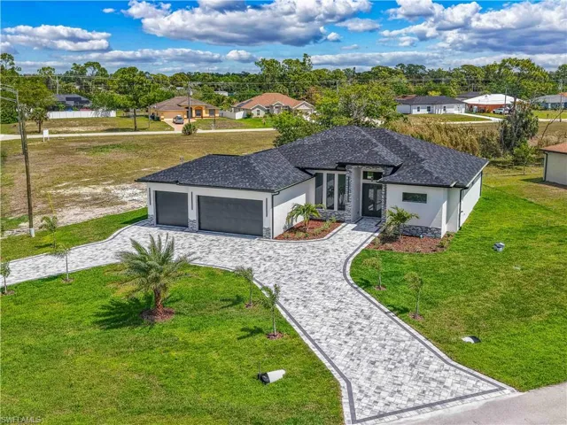 View of front of house with decorative driveway, a front lawn, an attached garage, and stucco siding