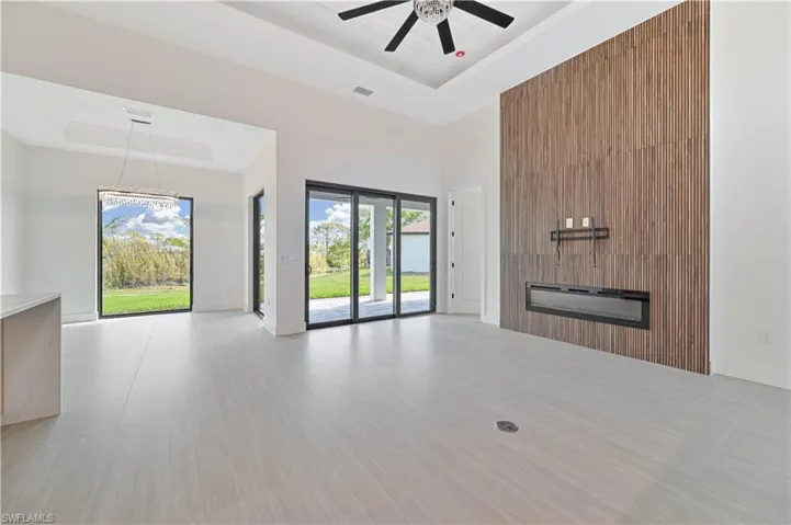 Unfurnished living room with a high tray ceiling and a ceiling fan