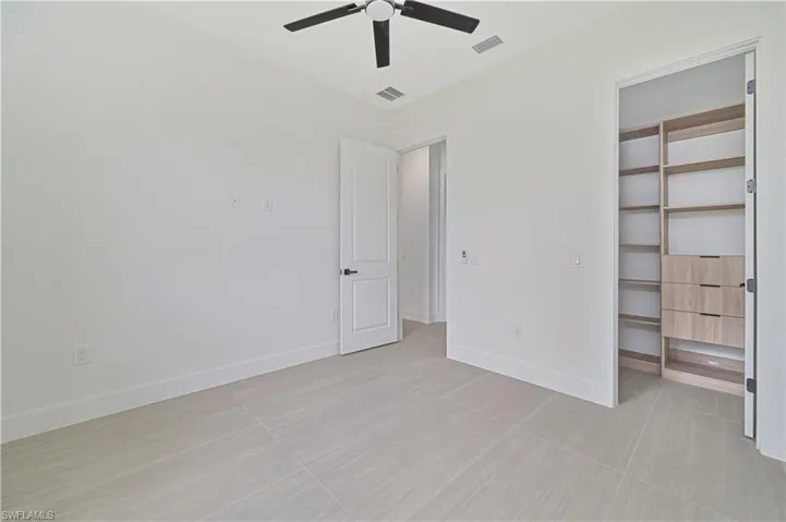 Unfurnished bedroom with a walk in closet and ceiling fan