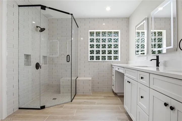 BRAND-NEW quartz counters, white cabinetry, marble-look tile, subway tile detailing and a NEW glass shower enclosure.