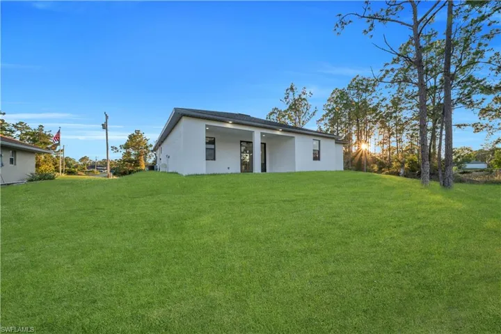 Rear view of property with stucco siding, a lawn, and a patio area