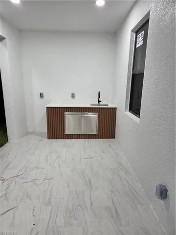 Washroom with hookup for an electric dryer, light marble finish flooring, and recessed lighting