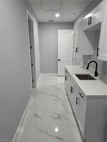 Bathroom featuring light marble finish floors, vanity, and a marble finish shower