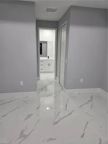 Kitchen featuring stainless steel refrigerator with ice dispenser, white cabinetry, light marble finish flooring, recessed lighting, and light stone countertops