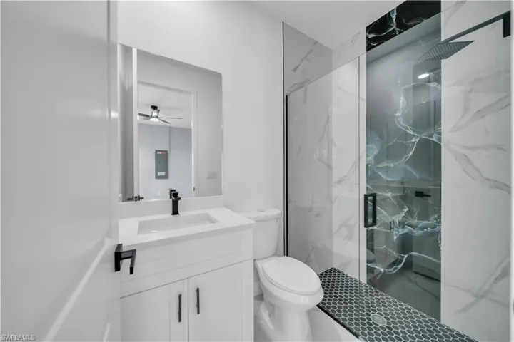 Full bathroom with a marble finish shower, vanity, and a ceiling fan