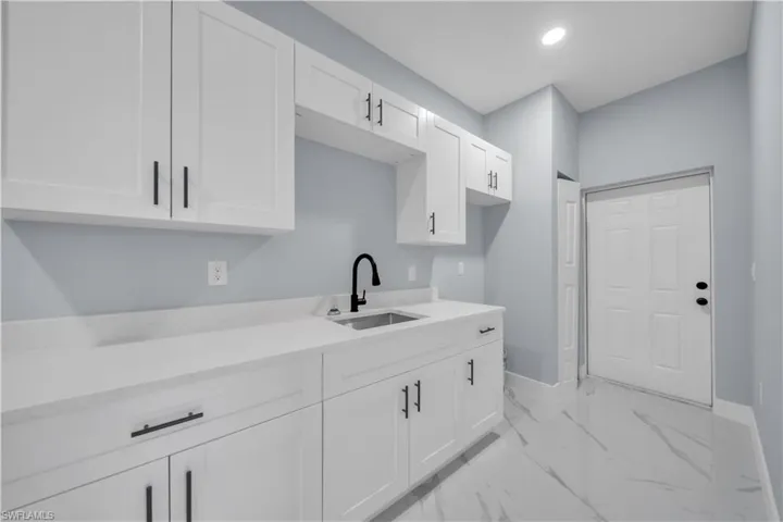 Kitchen featuring white cabinetry, light marble finish floors, light stone counters, and recessed lighting