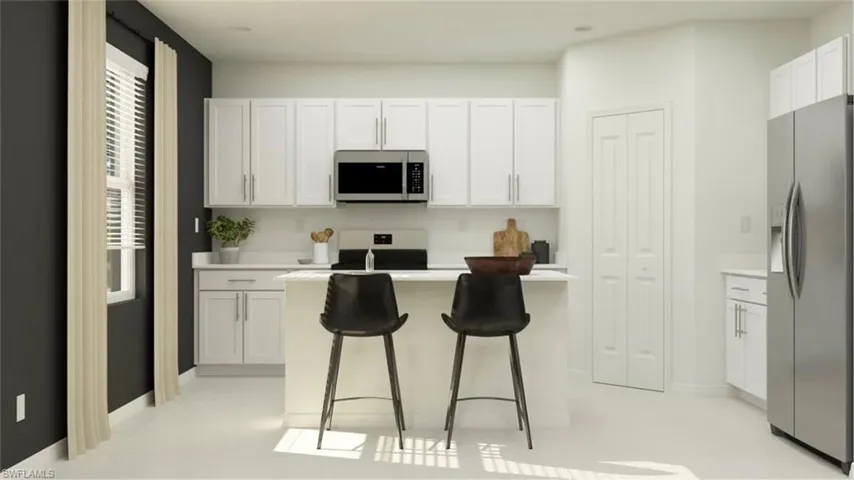 Contemporary kitchen featuring white cabinetry, stainless steel microwave, and white countertops