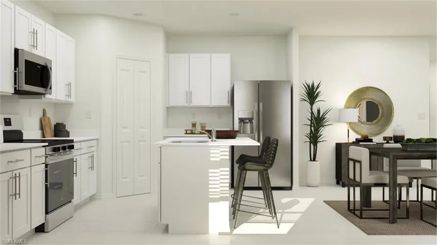 Contemporary kitchen and dining area featuring white cabinetry, stainless steel appliances, and a central island with seating