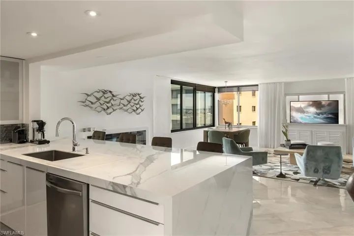 Kitchen with white cabinetry, a peninsula, light stone countertops, modern cabinets, and recessed lighting