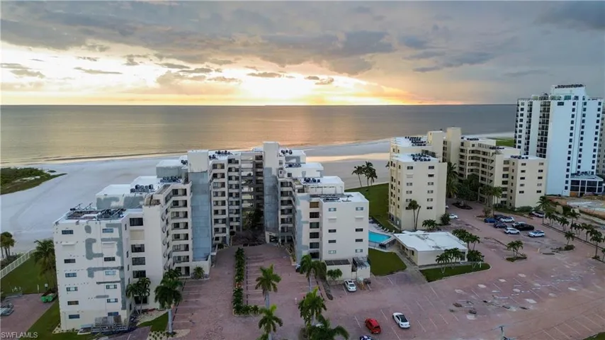 Aerial view at dusk of a view of apartment building / complex and view of water and beach