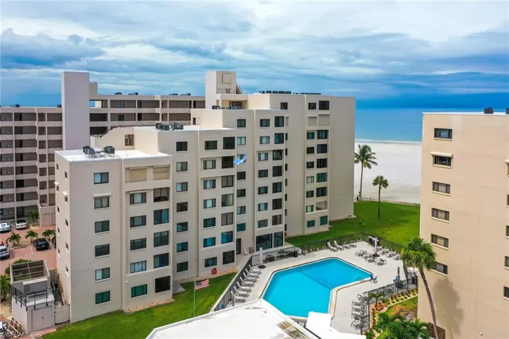 View of apartment building / complex with uncovered parking and view of water and beach
