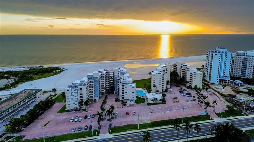 Aerial view at dusk of a view of apartment building / complex and view of water and beach