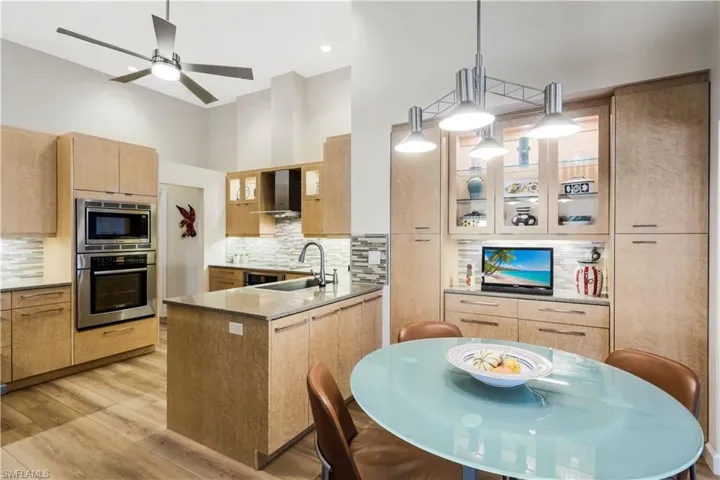 Vaulted ceiling kitchen featuring a central island, wood-finish cabinetry, stainless steel appliances, and a tile backsplash