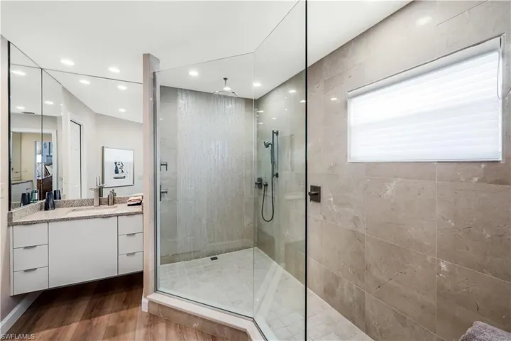 Walk-in glass shower with a rain shower head, hand-held shower, and tiled walls