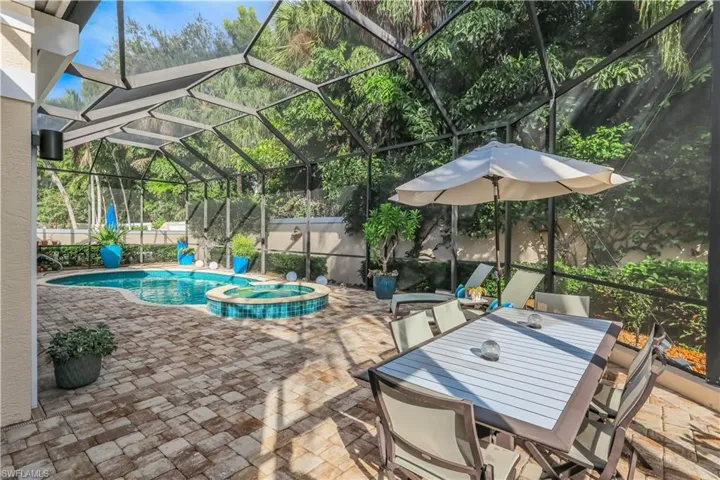 Screened enclosure featuring a swimming pool, integrated spa with tile detailing, and paver patio