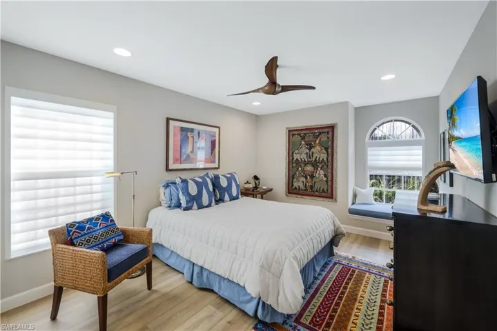Recessed lighting, wood-finish flooring, ceiling fan, window with horizontal blinds, and an arched window with a built-in window bench