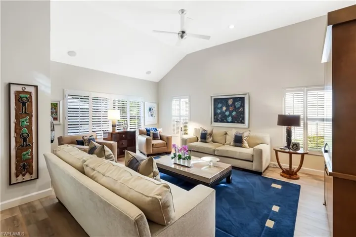 Vaulted ceiling with recessed lighting, wood-finish flooring, plantation shutters, and a ceiling fan