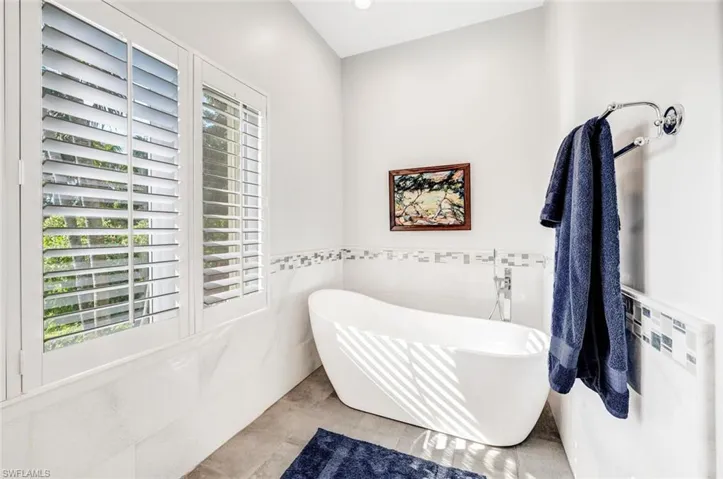 Bathroom with tile walls, a bathing tub, tile patterned floors, and plenty of natural light