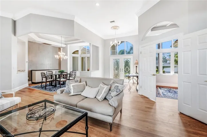 Living room with light hardwood / wood-style flooring, ornamental molding, a chandelier, and french doors
