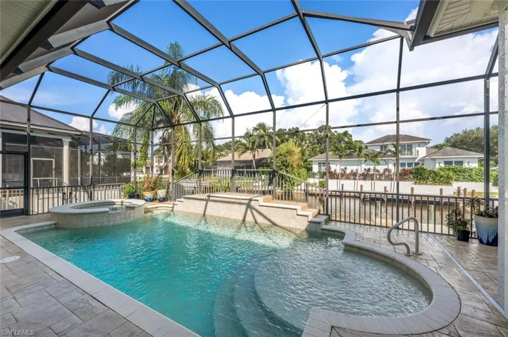 View of swimming pool featuring glass enclosure, an in ground hot tub, and a patio area