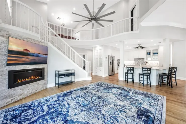 Living room featuring a fireplace, light wood-type flooring, a towering ceiling, and crown molding