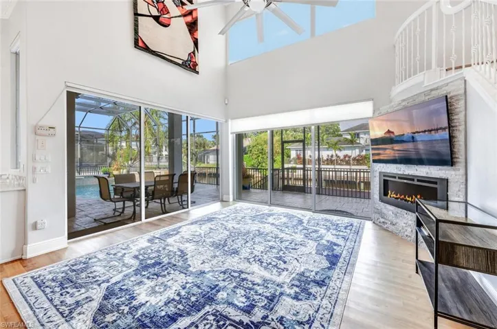 Living room featuring a towering ceiling, hardwood / wood-style floors, ceiling fan, and a large fireplace