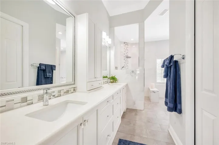 Bathroom with vanity, a tile shower, and tile patterned floors