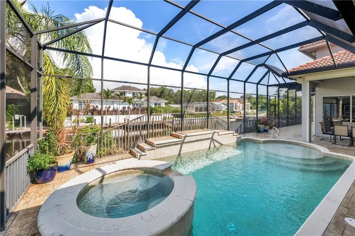 View of pool featuring an in ground hot tub, a lanai, a water view, and a patio area