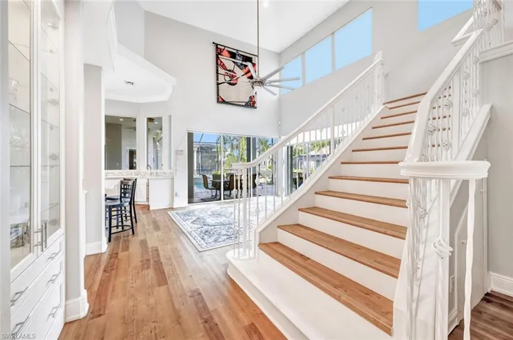 Stairway with a high ceiling, wood-type flooring, plenty of natural light, and ceiling fan
