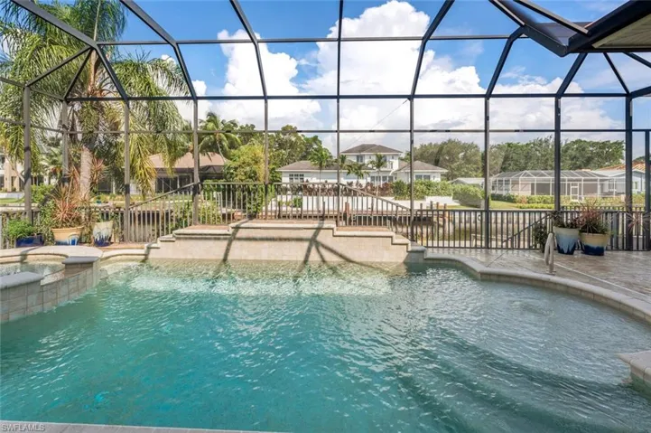View of pool with an in ground hot tub, a lanai, a water view, and a patio area