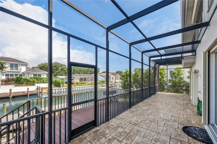 View of patio with glass enclosure and a water view